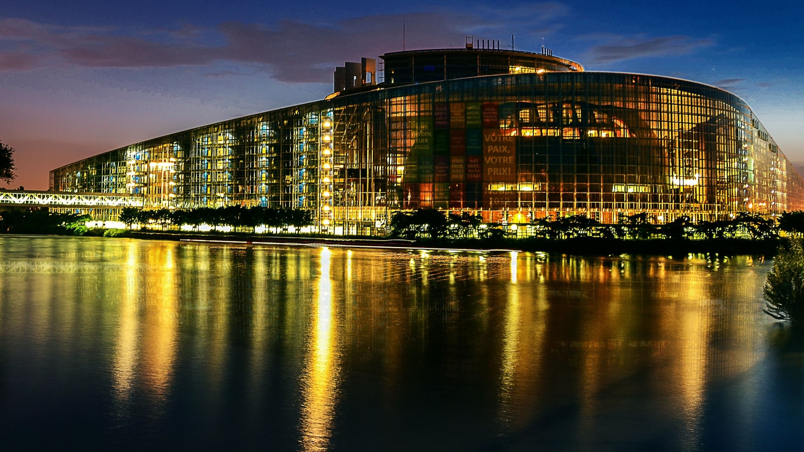 Das Gebäude des Europäischen Parlaments in Straßburg bei Nacht, gespiegelt im Wasser