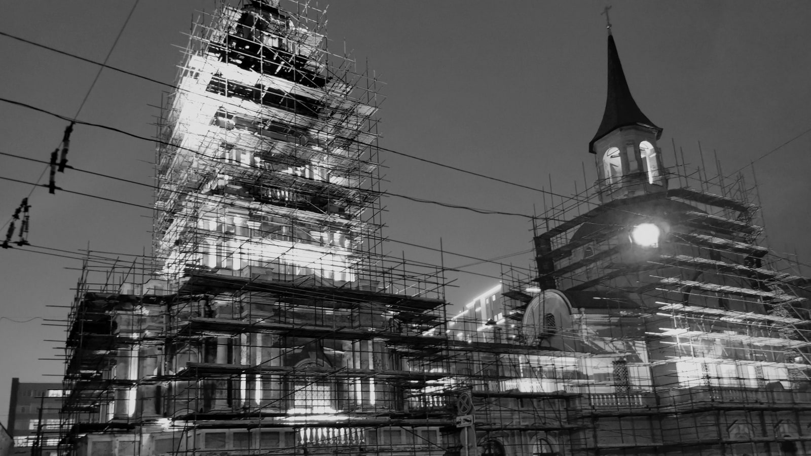 Zwei eingerüstete Kirchtürme bei Nacht, Schwarzweißaufnahme