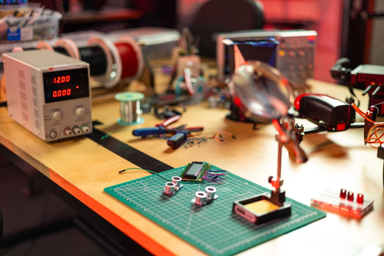 Elektronik-Werkbank mit Labornetzteil, Messgerät und einer Platine mit Display auf der Schneidematte