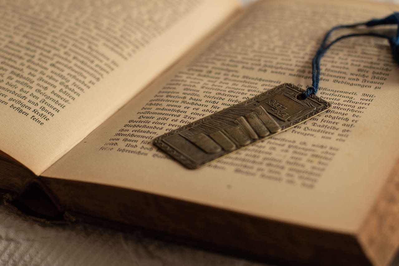 Aufgeschlagenes altes Buch mit filigranem Metall-Lesezeichen auf der bedruckten Seite