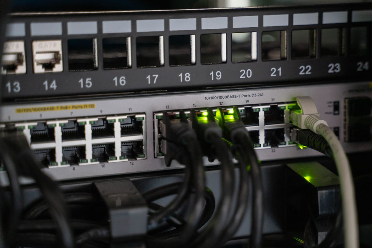 Netzwerk-Switch mit eingesteckten Patchkabeln und grün leuchtenden Statusanzeigen