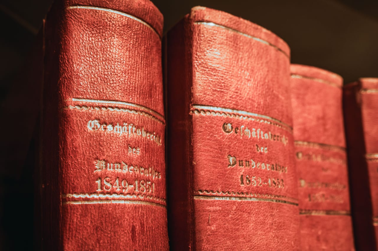 Reihe rot gebundener Gesetzbücher mit goldener Prägung in einem Bibliotheksregal