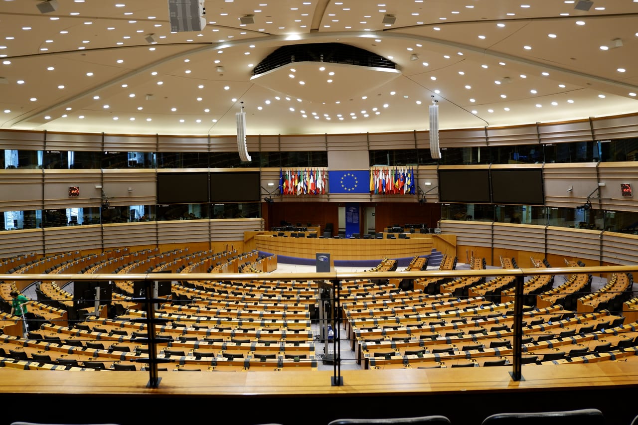 Leerer Plenarsaal des Europäischen Parlaments mit halbrund angeordneten Sitzreihen