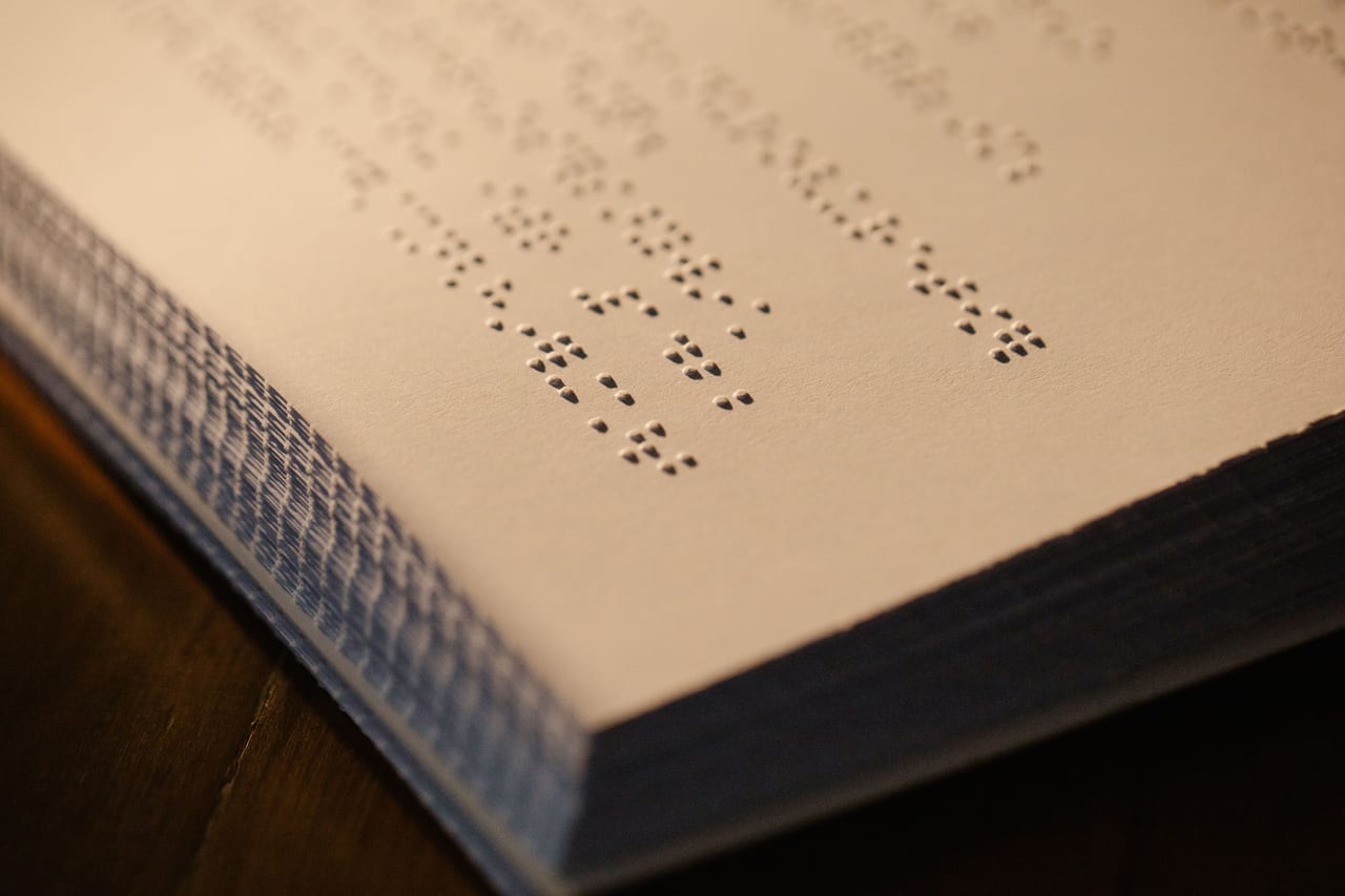 Aufgeschlagenes Buch mit Blindenschrift, die Punktmuster werfen im Streiflicht Schatten