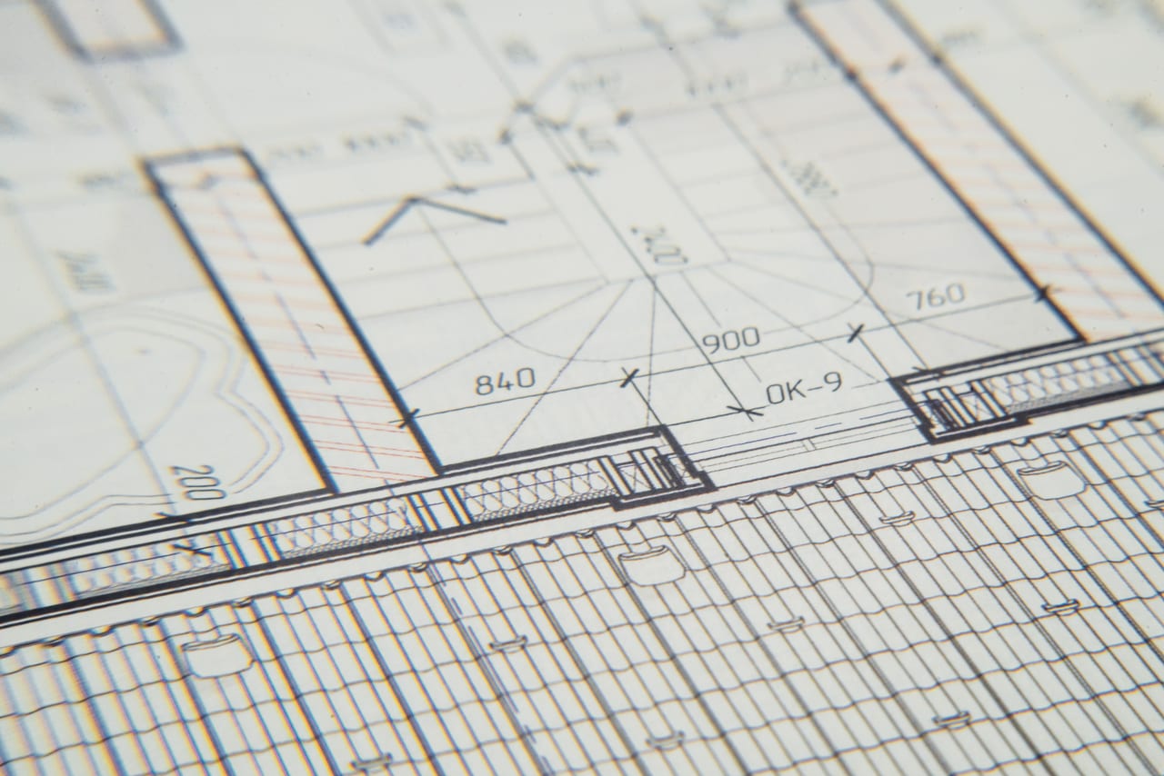 Nahaufnahme eines technischen Bauplans mit Maßlinien, Rastern und eingezeichneten Wänden