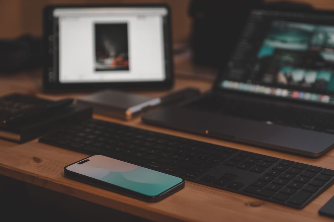 Tablet, Smartphone und Tastatur nebeneinander auf einem Schreibtisch, alle Bildschirme dunkel