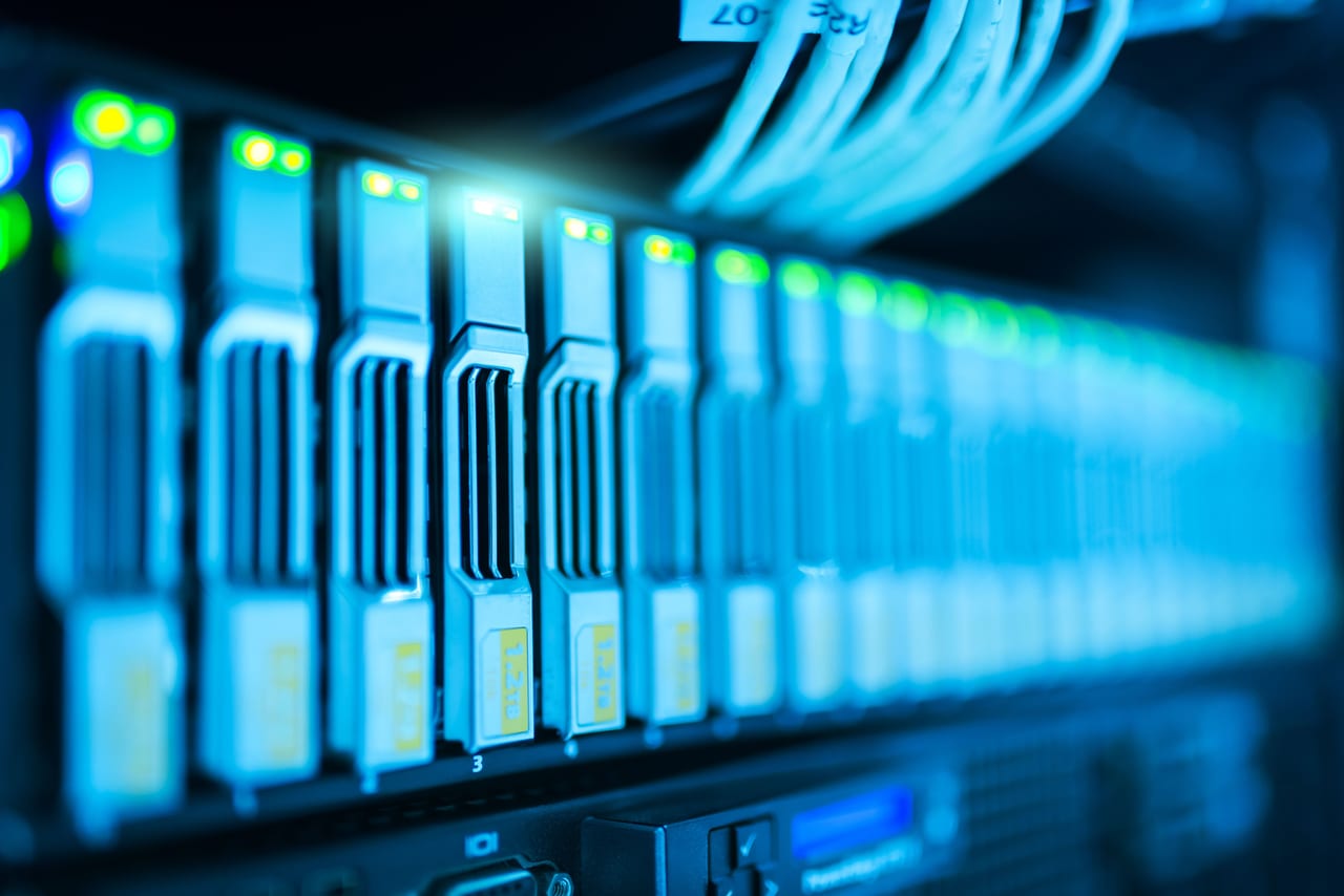 Reihe von Festplatteneinschüben in einem Server mit grün und blau leuchtenden Statusanzeigen
