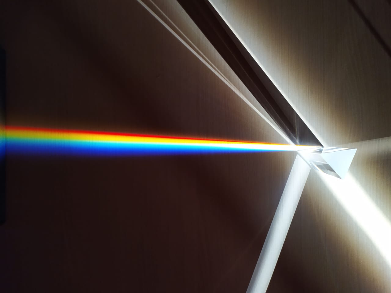 Lichtstrahl fällt auf ein Glasprisma und wird in ein farbiges Spektrum zerlegt